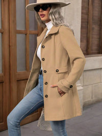 Woman wearing a beige coat, sunglasses, and a hat in an urban setting.