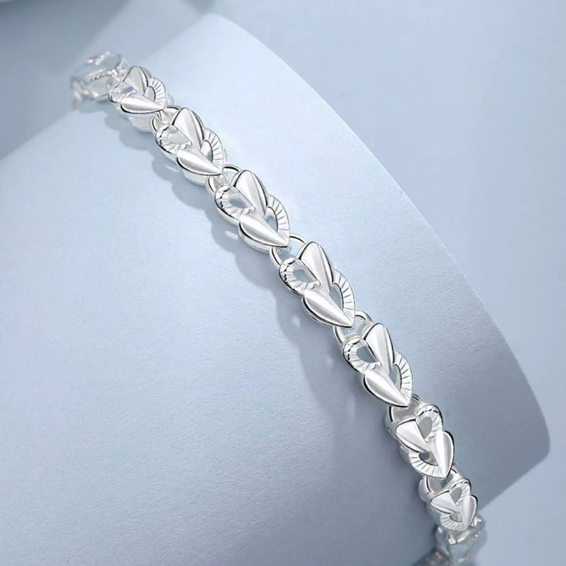 Silver bracelet with leaf-like design on a light blue background
