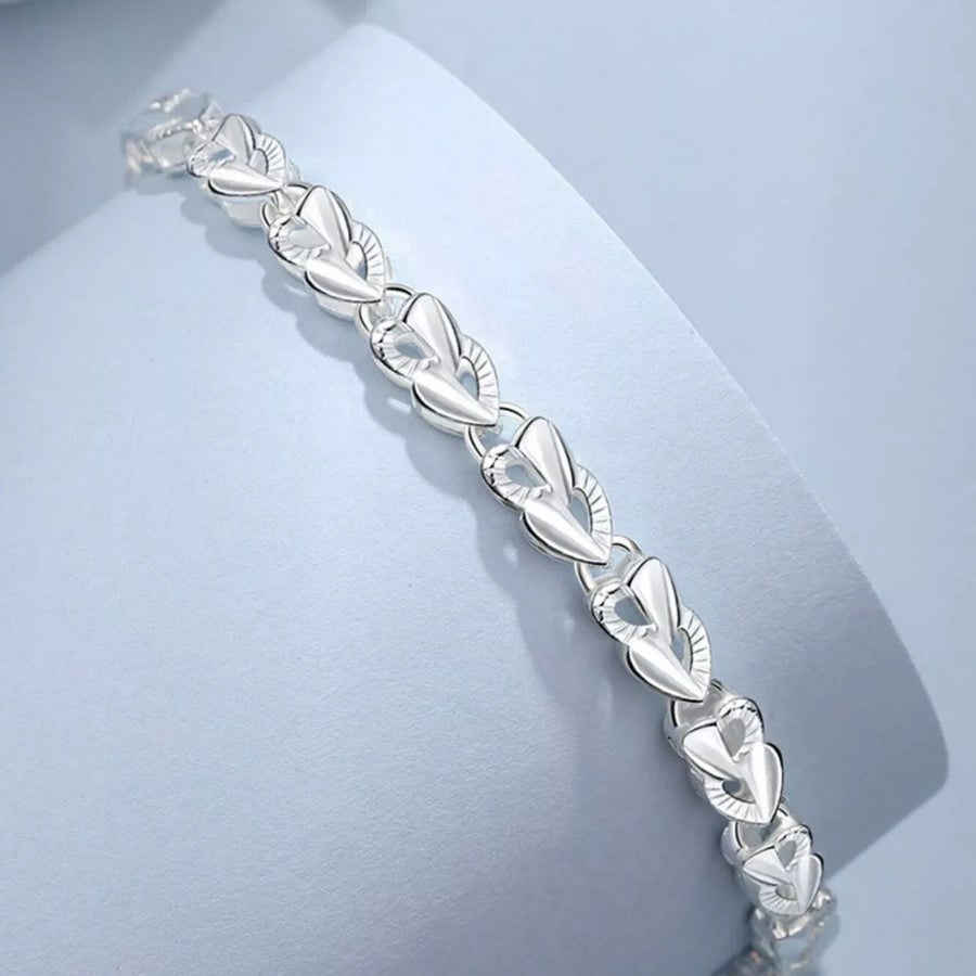 Silver bracelet with leaf-like design on a light blue background
