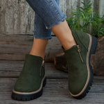 Green ankle boots with zippers worn by a person on wooden steps.