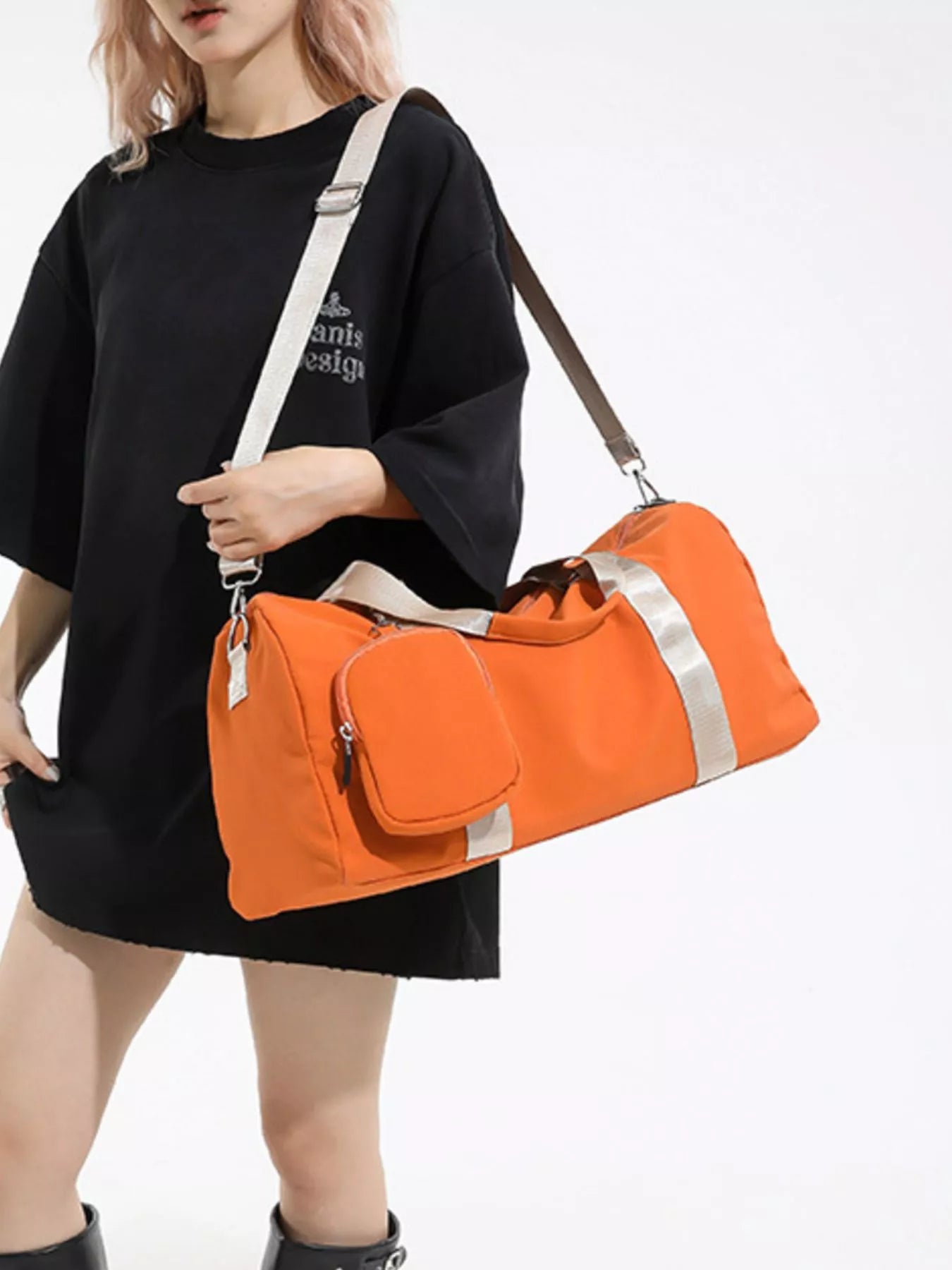 Person holding an orange duffel bag with a white strap on a plain background