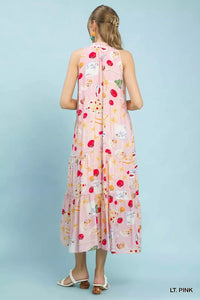 Woman wearing a light pink sleeveless dress with colorful floral pattern on a light blue background