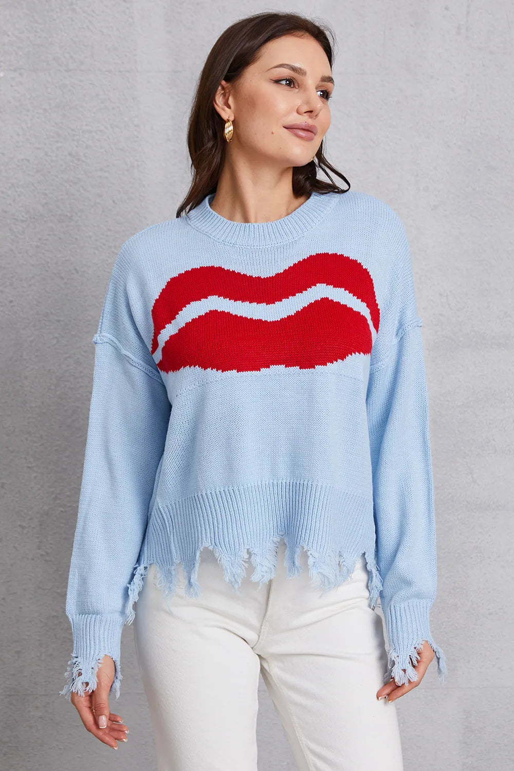 Woman wearing a light blue sweater with red lips design against a gray background