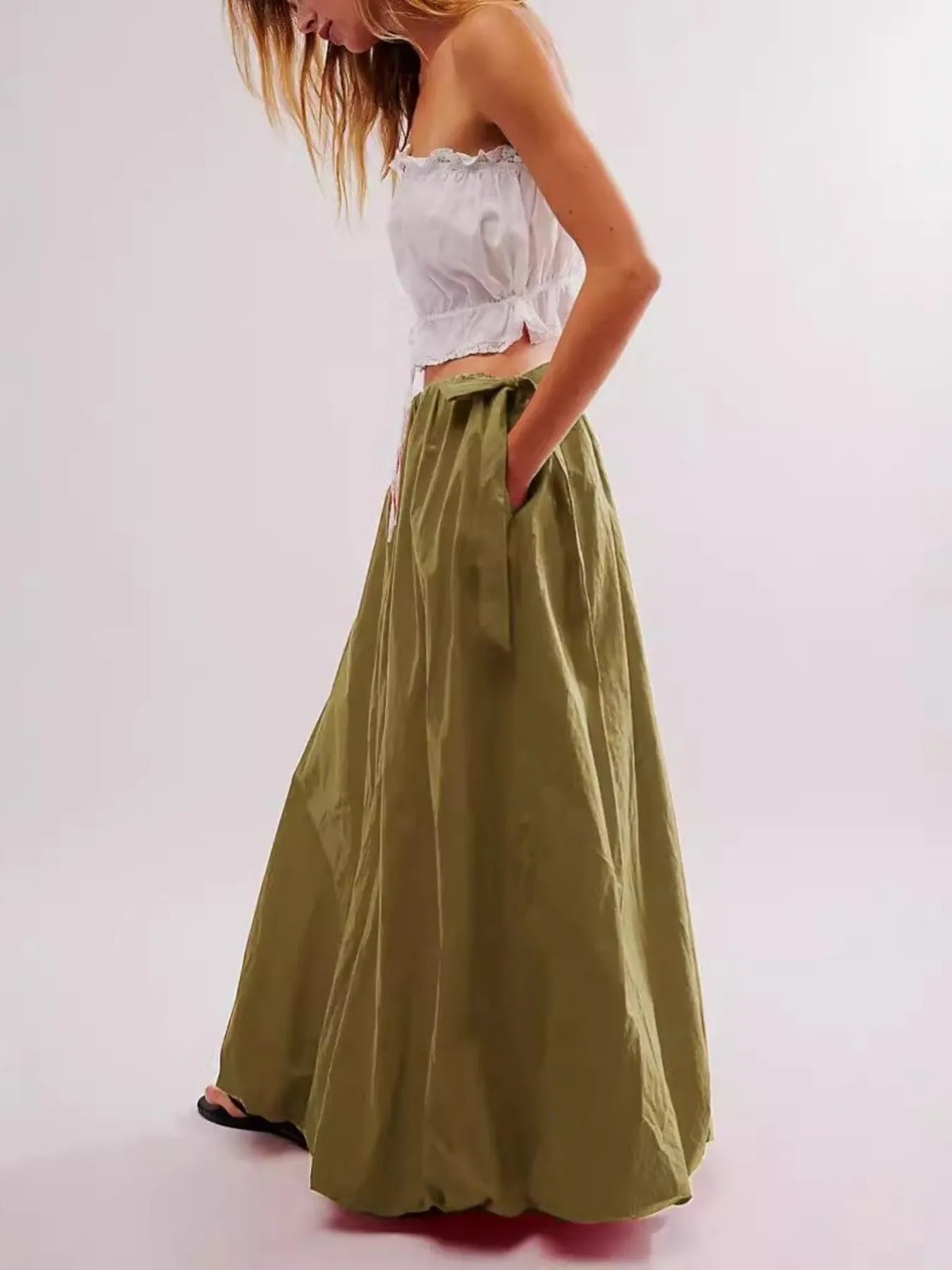 Woman wearing a white top and green skirt on a plain background