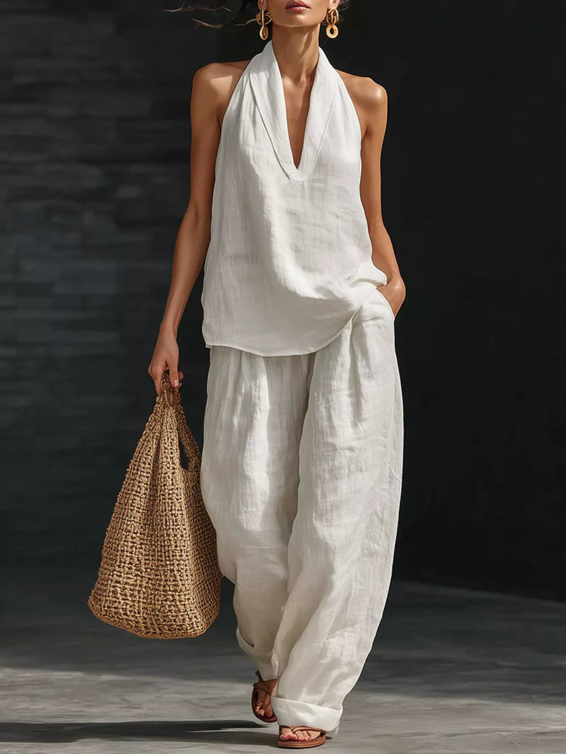 Woman in a white outfit holding a woven bag against a dark background