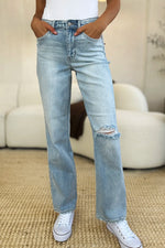 Person wearing light blue jeans with a slight distressed look, standing on a carpeted floor.