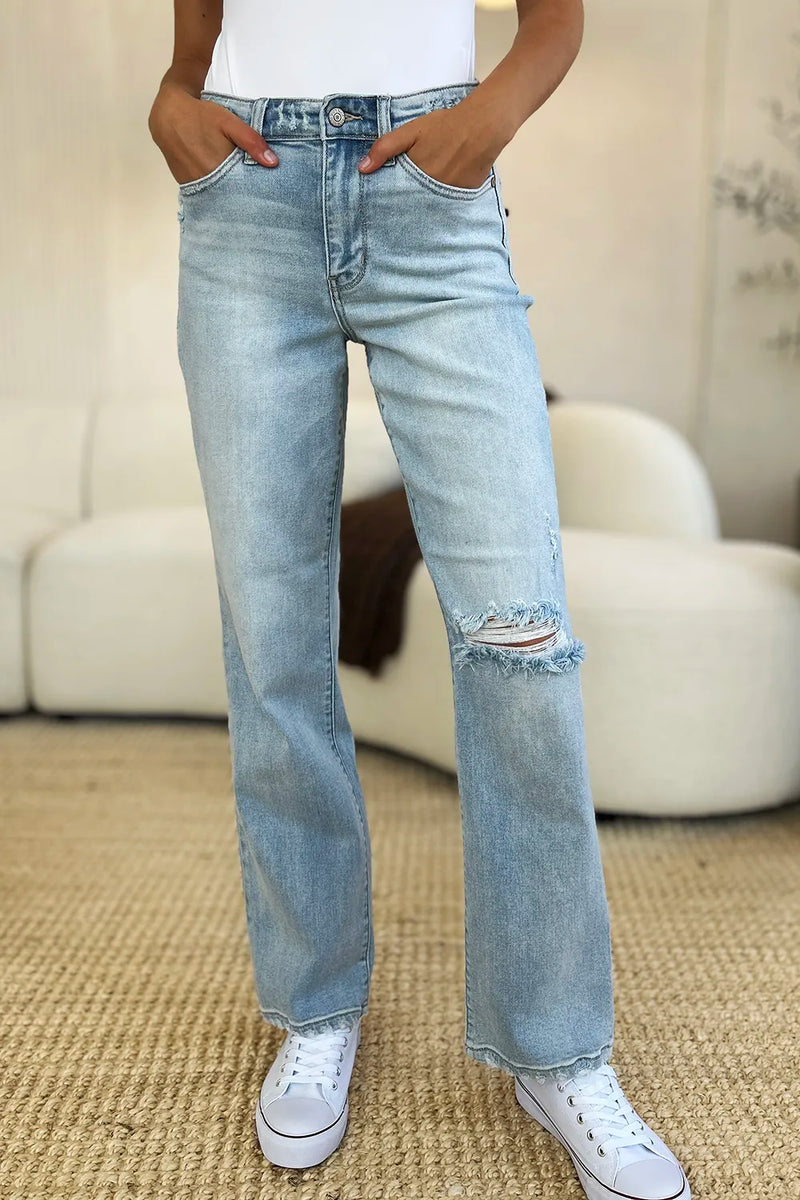 Person wearing light blue jeans with a slight distressed look, standing on a carpeted floor.
