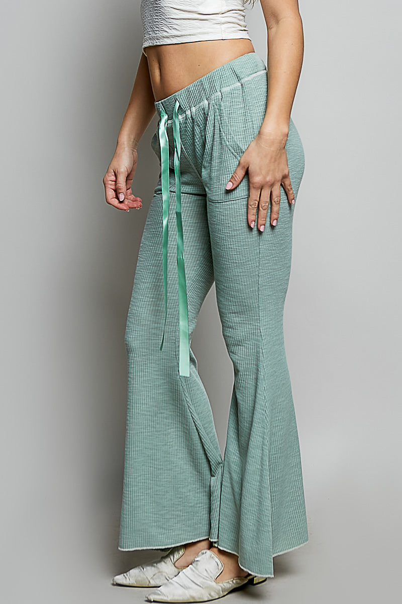 Person wearing teal checkered pants with a white top on a gray background
