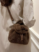 Brown fur bag worn over shoulder against a neutral background