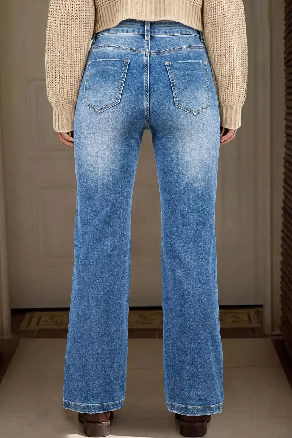 Person wearing blue jeans from behind with a neutral background
