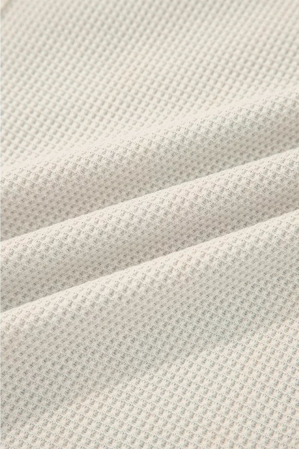 Close-up of textured beige fabric with a waffle pattern
