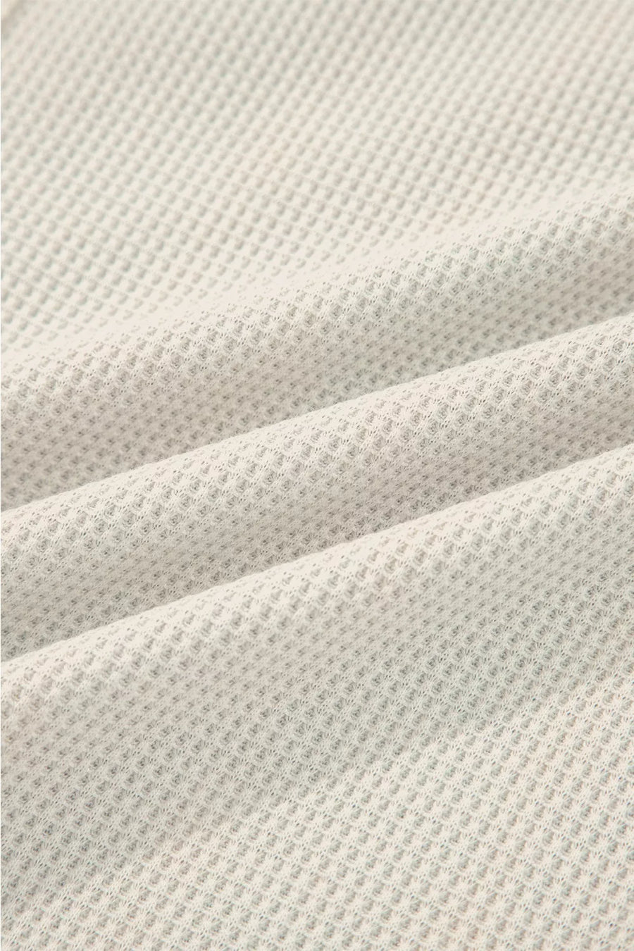 Close-up of textured beige fabric with a waffle pattern