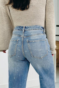 Person wearing light blue jeans and a beige sweater in an indoor setting