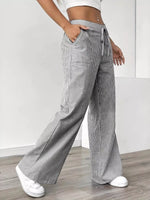 Person wearing gray and white striped wide-leg pants with a white background