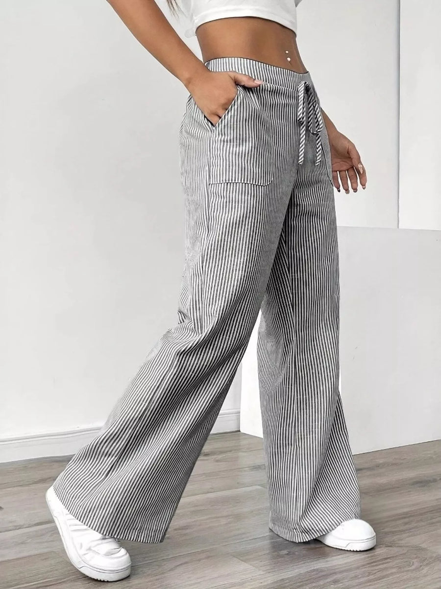 Person wearing gray and white striped wide-leg pants with a white background