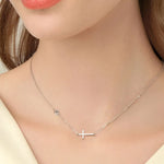 Silver cross necklace on a mannequin with a neutral background