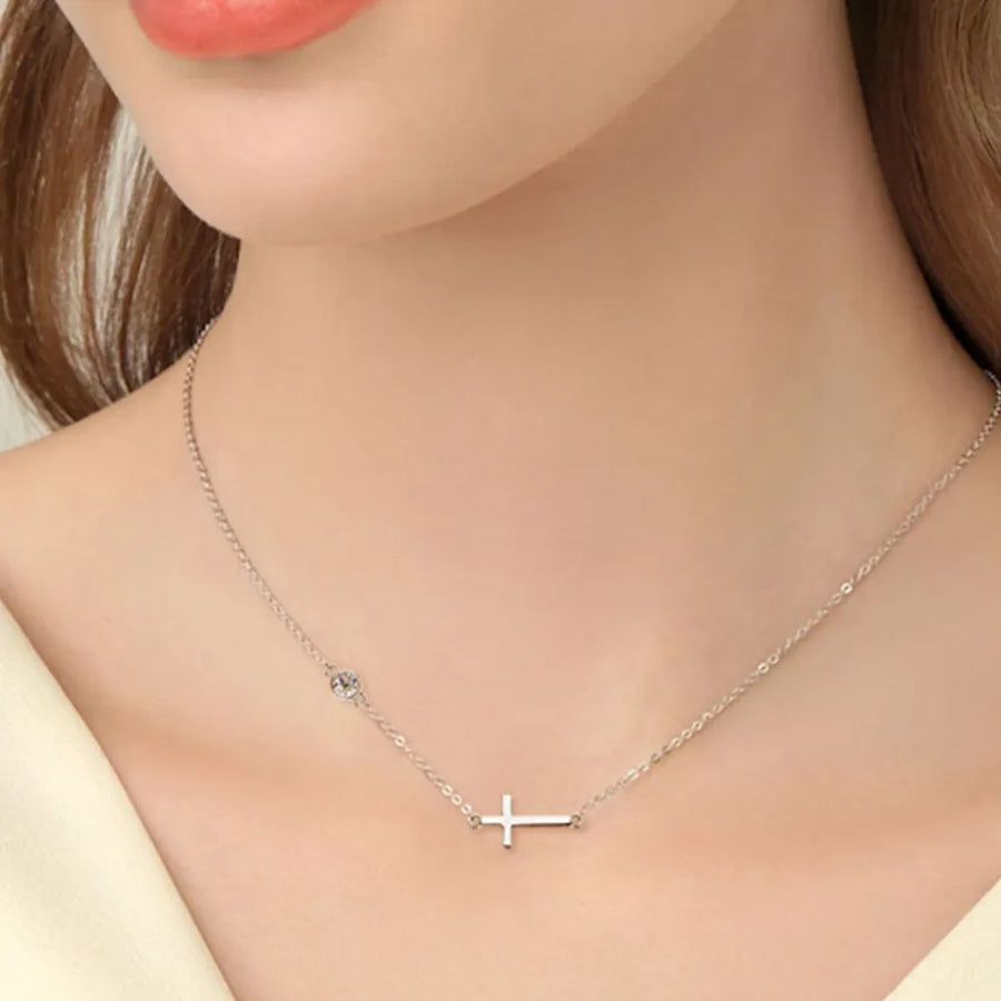 Silver cross necklace on a mannequin with a neutral background