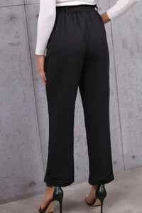 Black wide-leg pants worn by a person against a gray concrete wall.