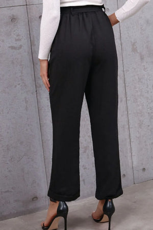 Black wide-leg pants worn by a person against a gray concrete wall.