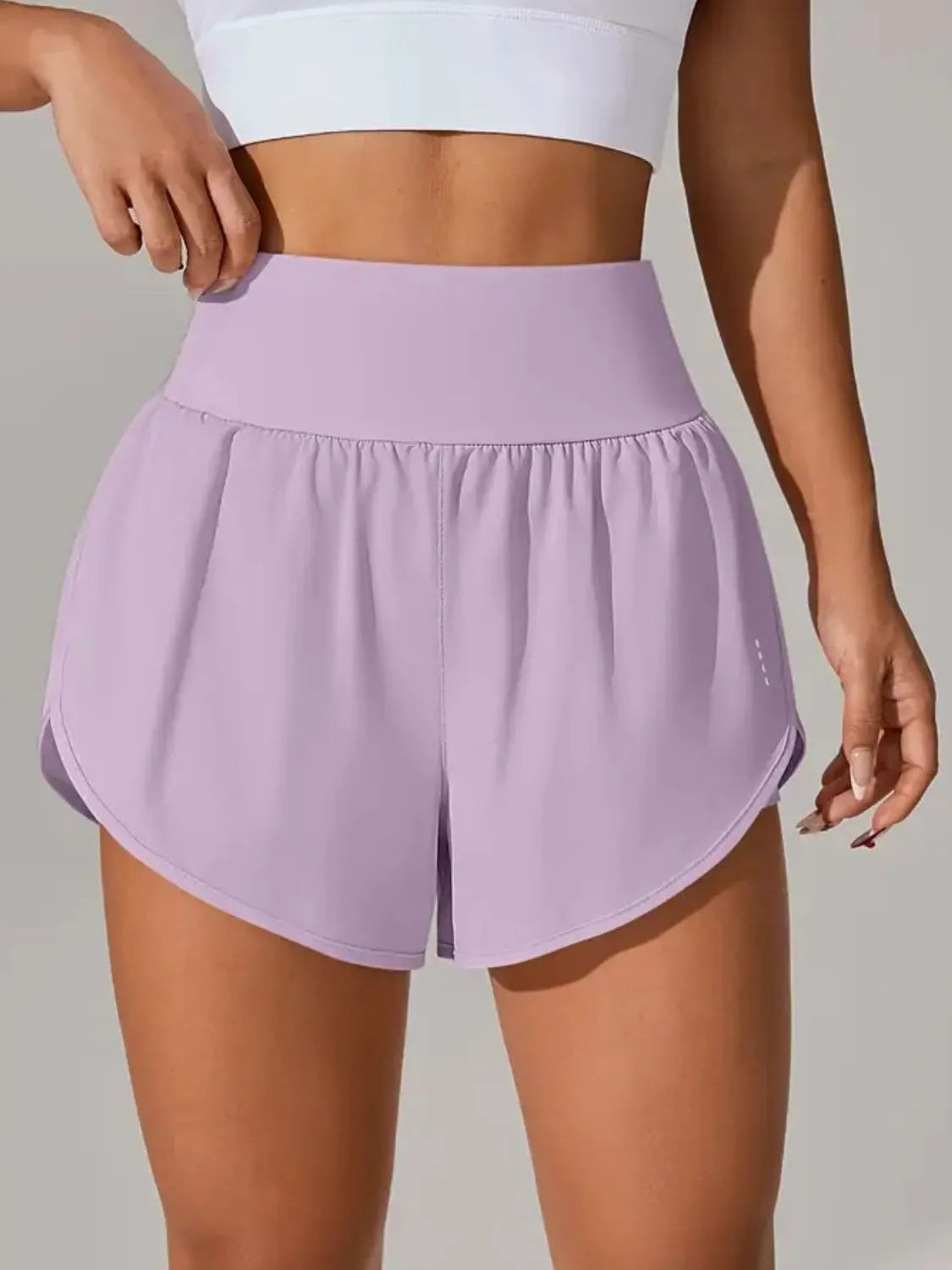 Person wearing light purple athletic shorts on a neutral background