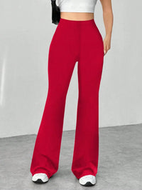 Red wide-leg pants worn by a person on a gray floor with a white wall background