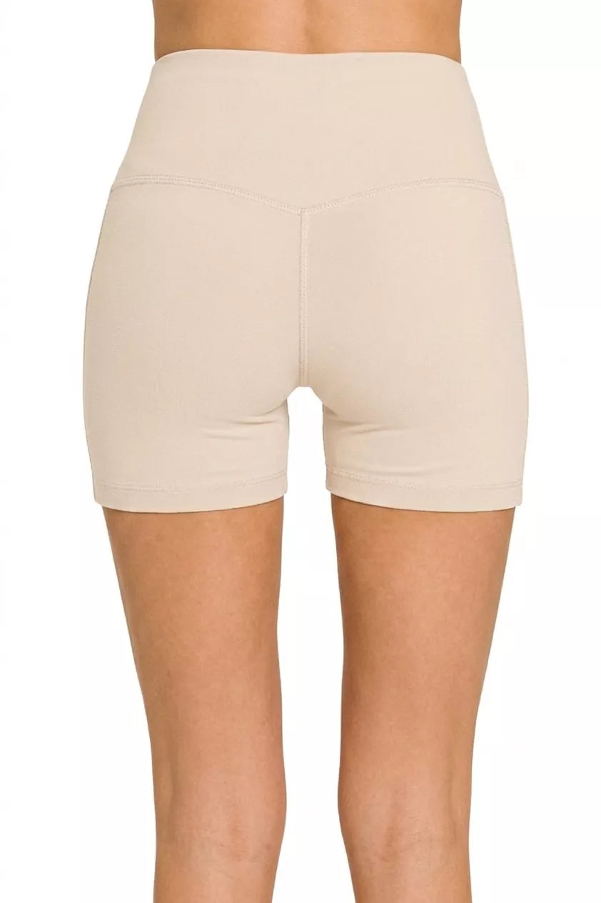 Beige high-waisted shorts worn by a person on a white background