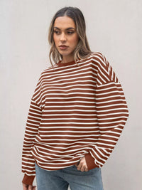 Woman wearing a brown and white striped sweater against a plain background