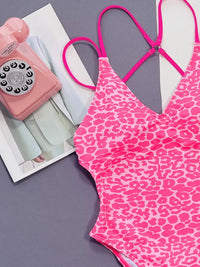 Pink leopard print swimsuit with a pink rotary phone on a gray surface