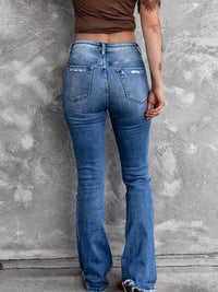 Person wearing blue flared jeans against a gray concrete wall.