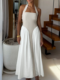 Woman wearing a white halter neck dress in an indoor setting.