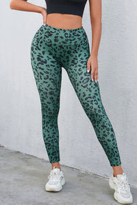 Person wearing green leopard print leggings against a gray wall.
