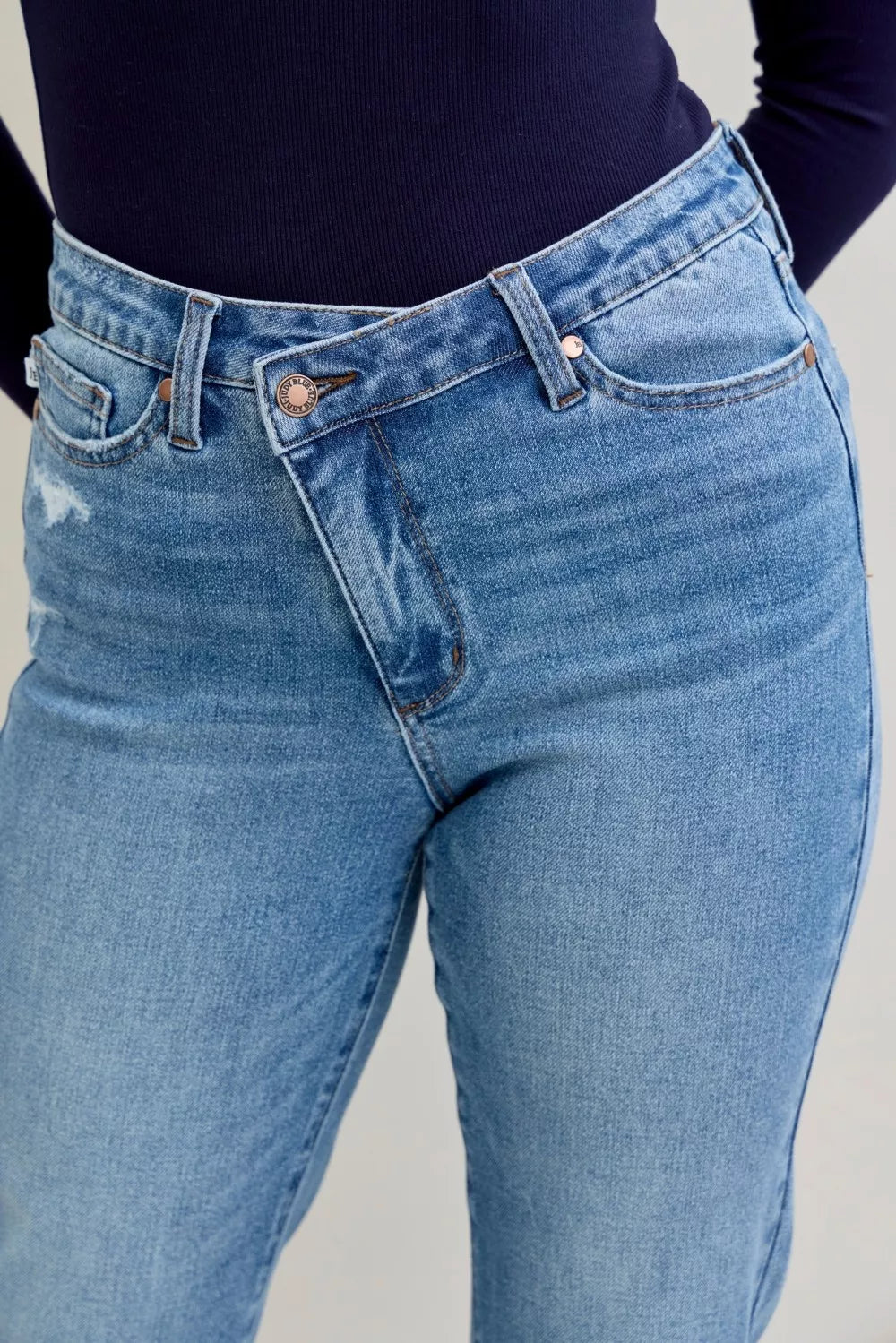Blue jeans worn by a person on a plain background