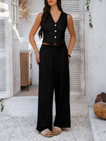Woman wearing a black sleeveless top and wide-leg pants standing in a bright outdoor setting.