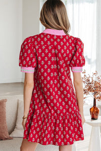 Woman wearing a red floral dress in a living room setting