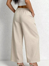 Beige wide-leg pants worn by a person on a light gray background