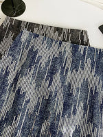Close-up of a blue and gray patterned rug on a white floor.