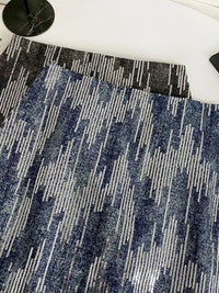 Close-up of a blue and gray patterned rug on a white floor.