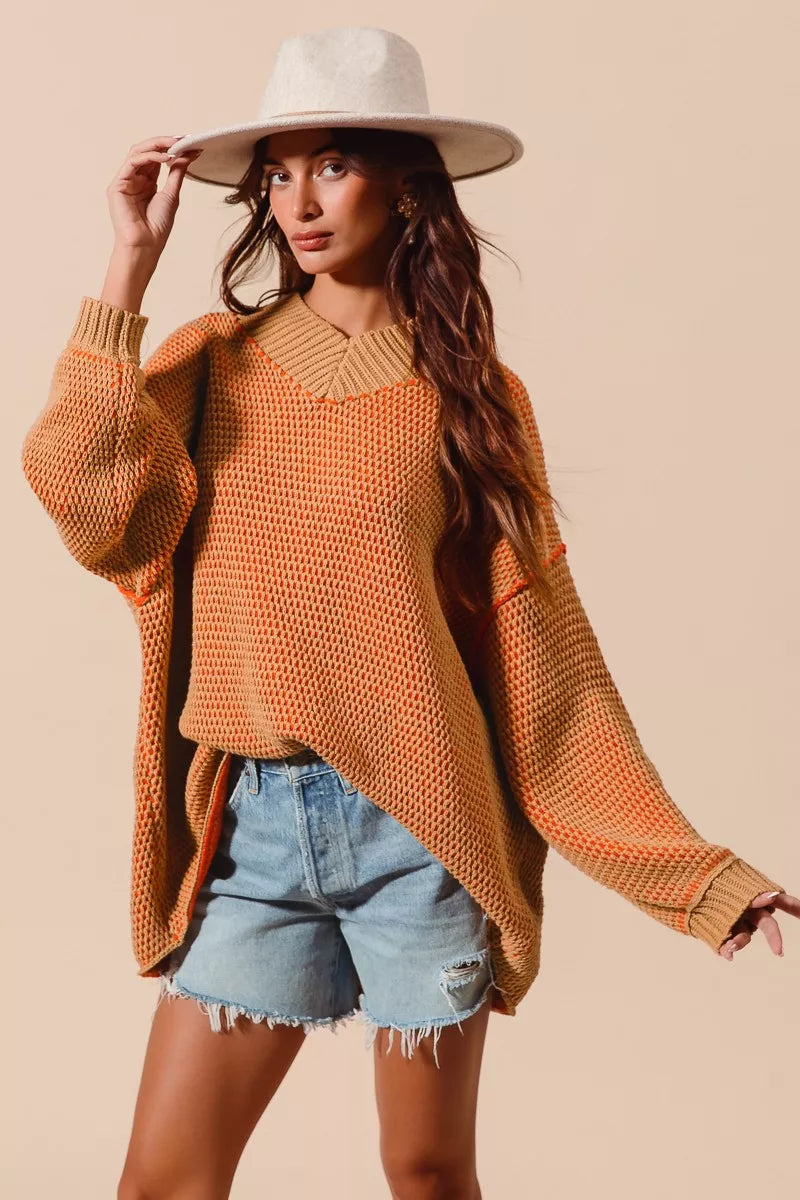 Woman wearing an orange sweater and denim shorts with a beige background