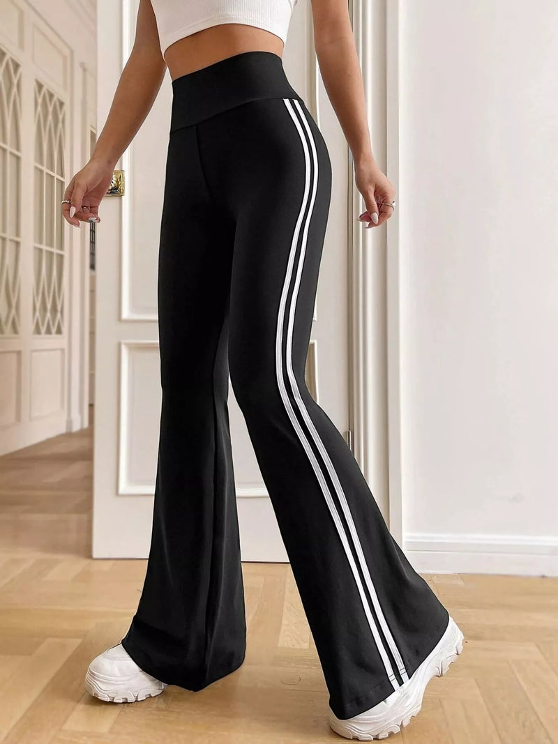 Black flared pants with white stripes worn by a person indoors.