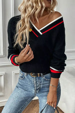 Person wearing a black sweater with red and white accents and blue jeans.