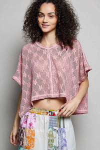 Woman wearing a pink crochet top and colorful patchwork pants against a gray background
