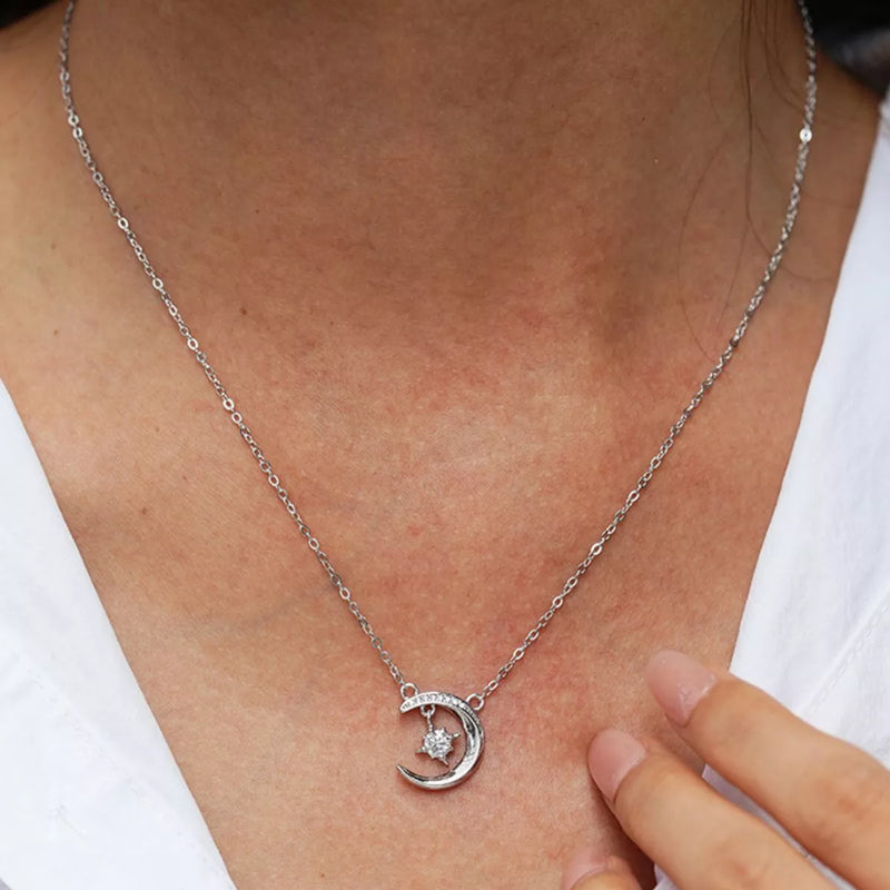 Silver necklace with a crescent moon pendant worn by a person