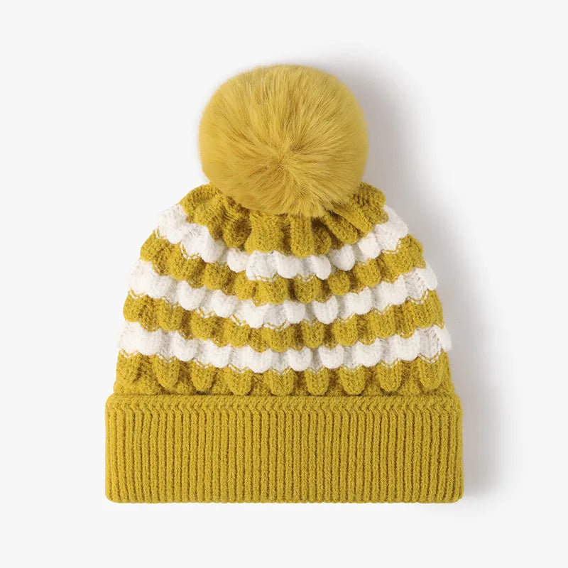 Yellow knit beanie with white stripes and a pom-pom on a white background