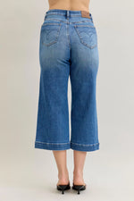 Blue jeans worn by a person on a plain background