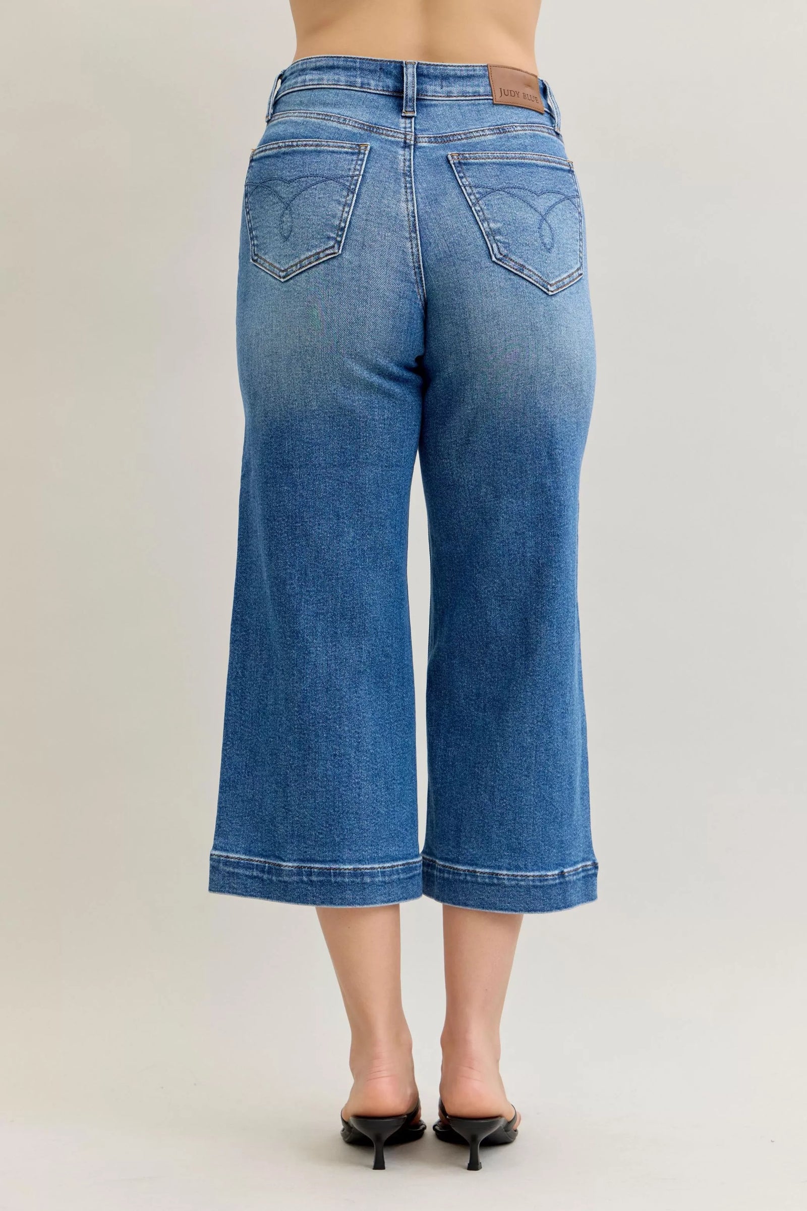 Blue jeans worn by a person on a plain background