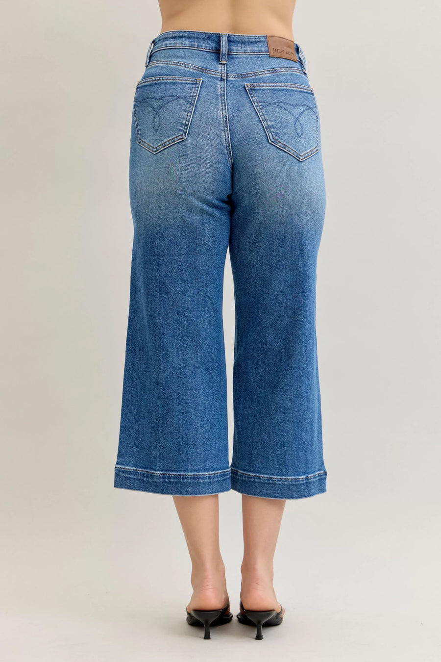 Blue jeans worn by a person on a plain background