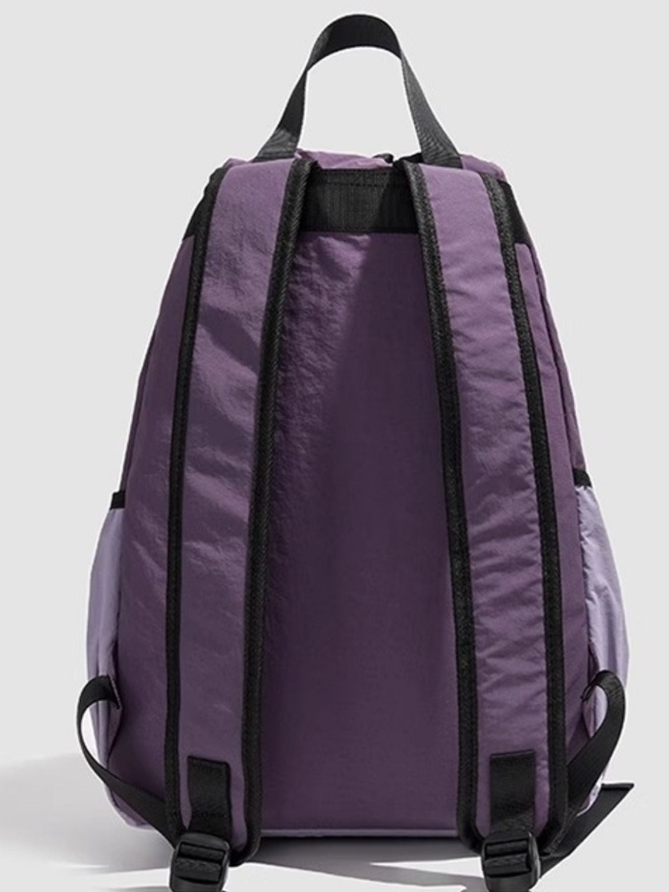 Purple backpack with black straps on a light gray background