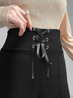 Black pants with lace-up design worn by a person, against a neutral background