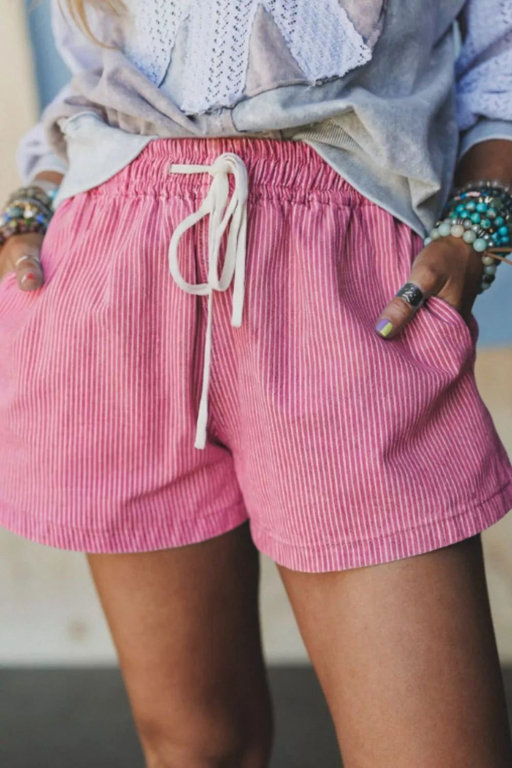 Person wearing pink shorts with a white drawstring, standing against a neutral background.