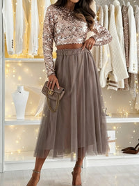 Woman wearing a sequin top and tulle skirt with a handbag in a store setting.